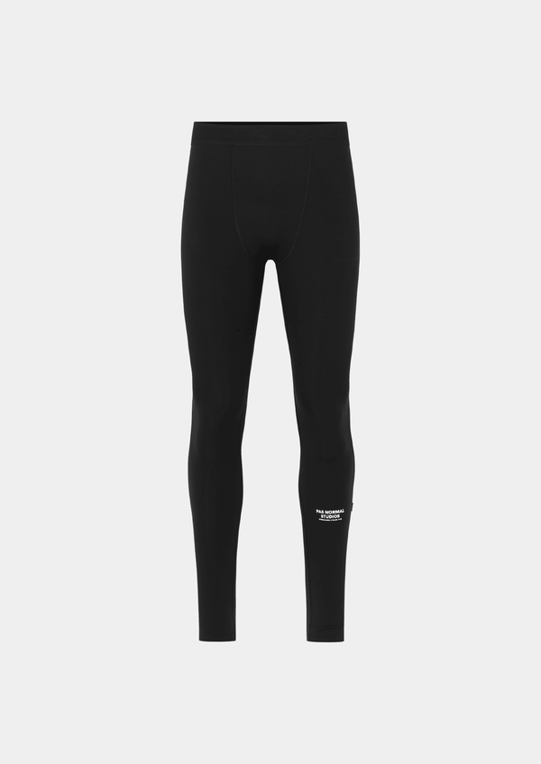 Front view of the Pas Normal Studios Men’s Balance Long Tights in the color black. Perforated elastic waistband and tight fit with Pas Normal Studio logo on lower left shin part of the tights.