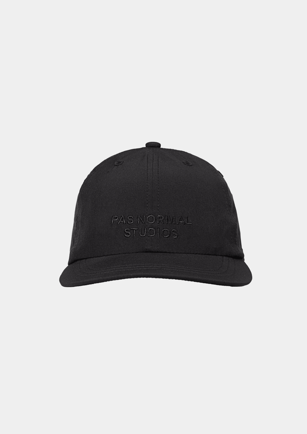 Front view of the Pas Normal Studios Balance Cap in the color Black. Six panel construction and ultra light nylon fabric.  Featuring a vented opening on the back and completed with a toggled drawstring, the cap is highly breathable and close-fitting, making it nearly undetectable during use.
