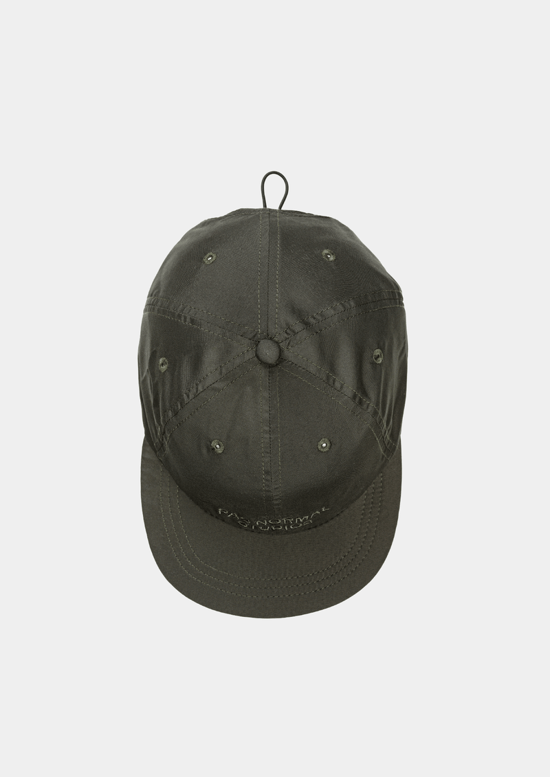 Top down view of the Pas Normal Studios Balance Cap in the color dark olive green. Six panel construction and ultra light nylon fabric. Featuring a vented opening on the back and completed with a toggled drawstring, the cap is highly breathable and close-fitting, making it nearly undetectable during use.