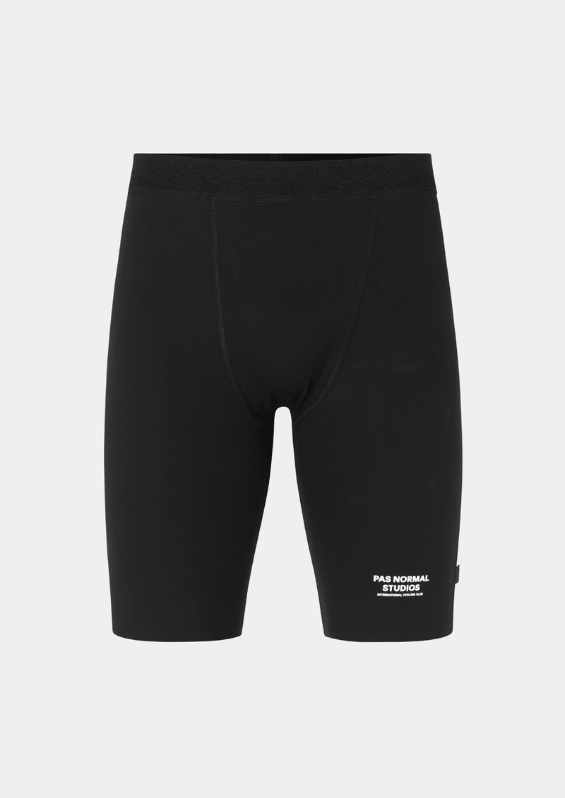Front view of the Pas Normal Studios Men’s Balance Short Tights in the color black. Perforated elastic waistband and tight fit with Pas Normal Studio font logo in white on lower left side. 