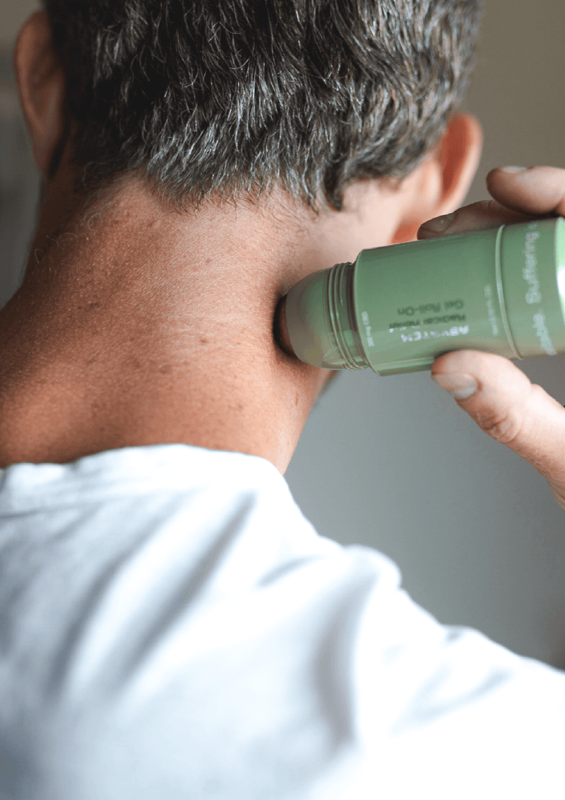 Photo of middle aged man applying the asystem radical relief gel with roller ball on the back of their neck.